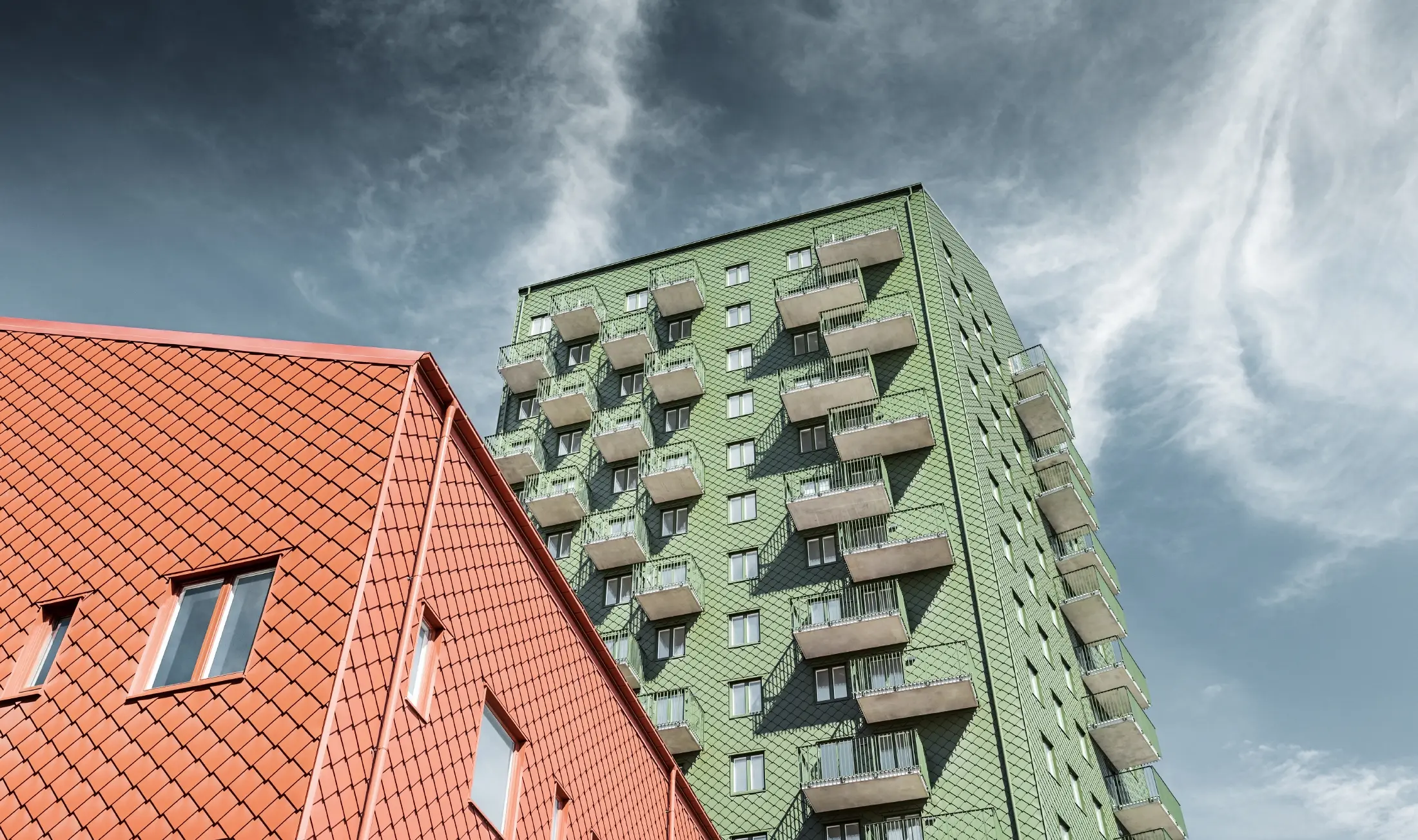 Výškové budovy s balkónmi s fasádnym riešením s PREFA fasádnou šablónou 29 × 29 vo farbe olivovozelená a tehlovočervená
