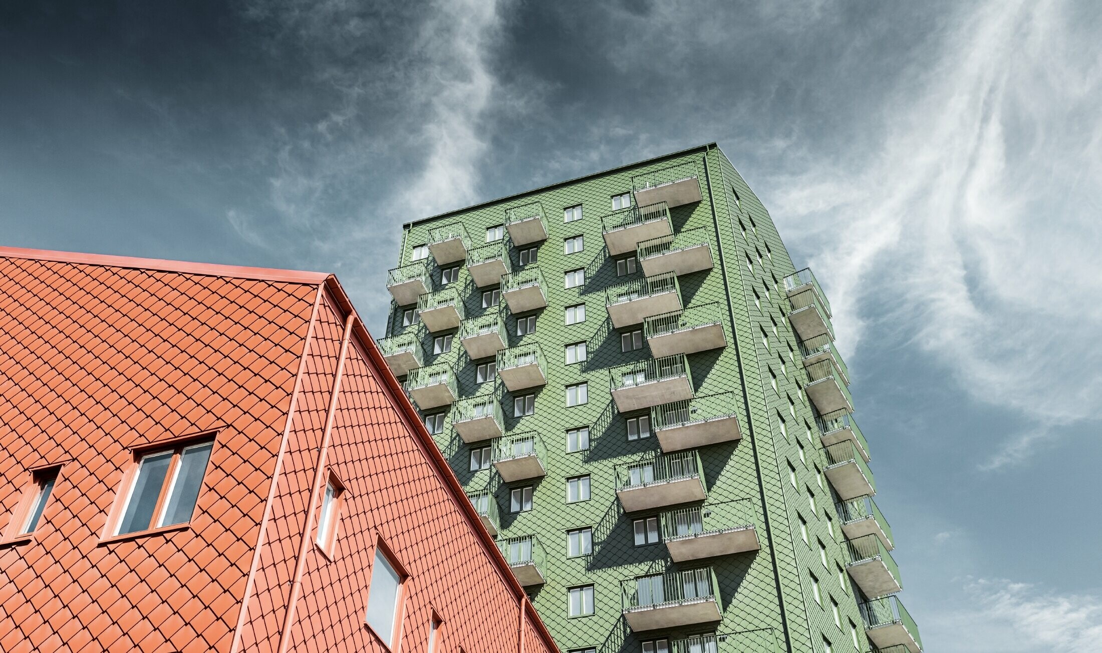 Výškové budovy s balkónmi s fasádnym riešením s PREFA fasádnou šablónou 29 × 29 vo farbe olivovozelená a tehlovočervená