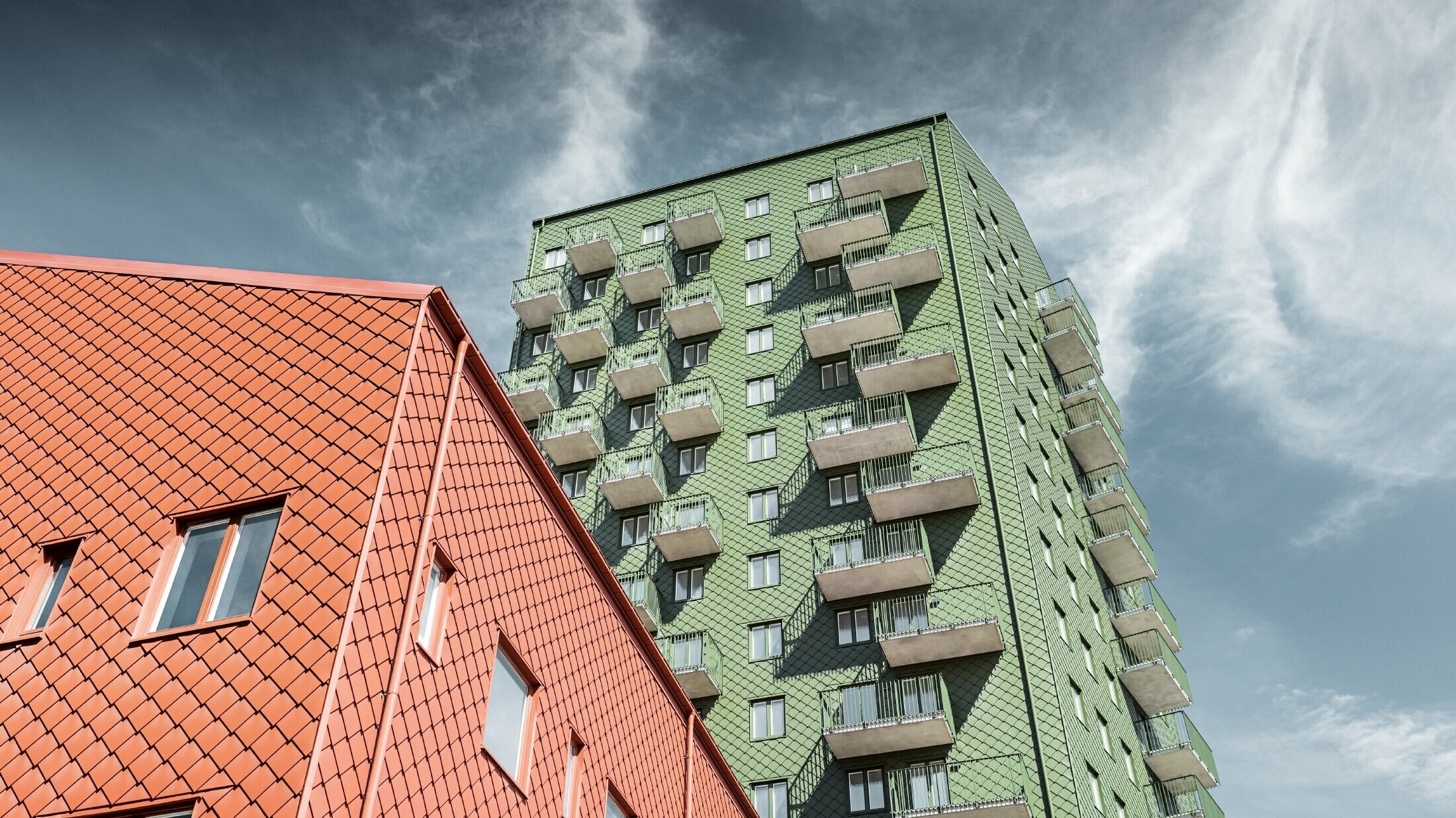 Výškové budovy s balkónmi s fasádnym riešením s PREFA fasádnou šablónou 29 × 29 vo farbe olivovozelená a tehlovočervená
