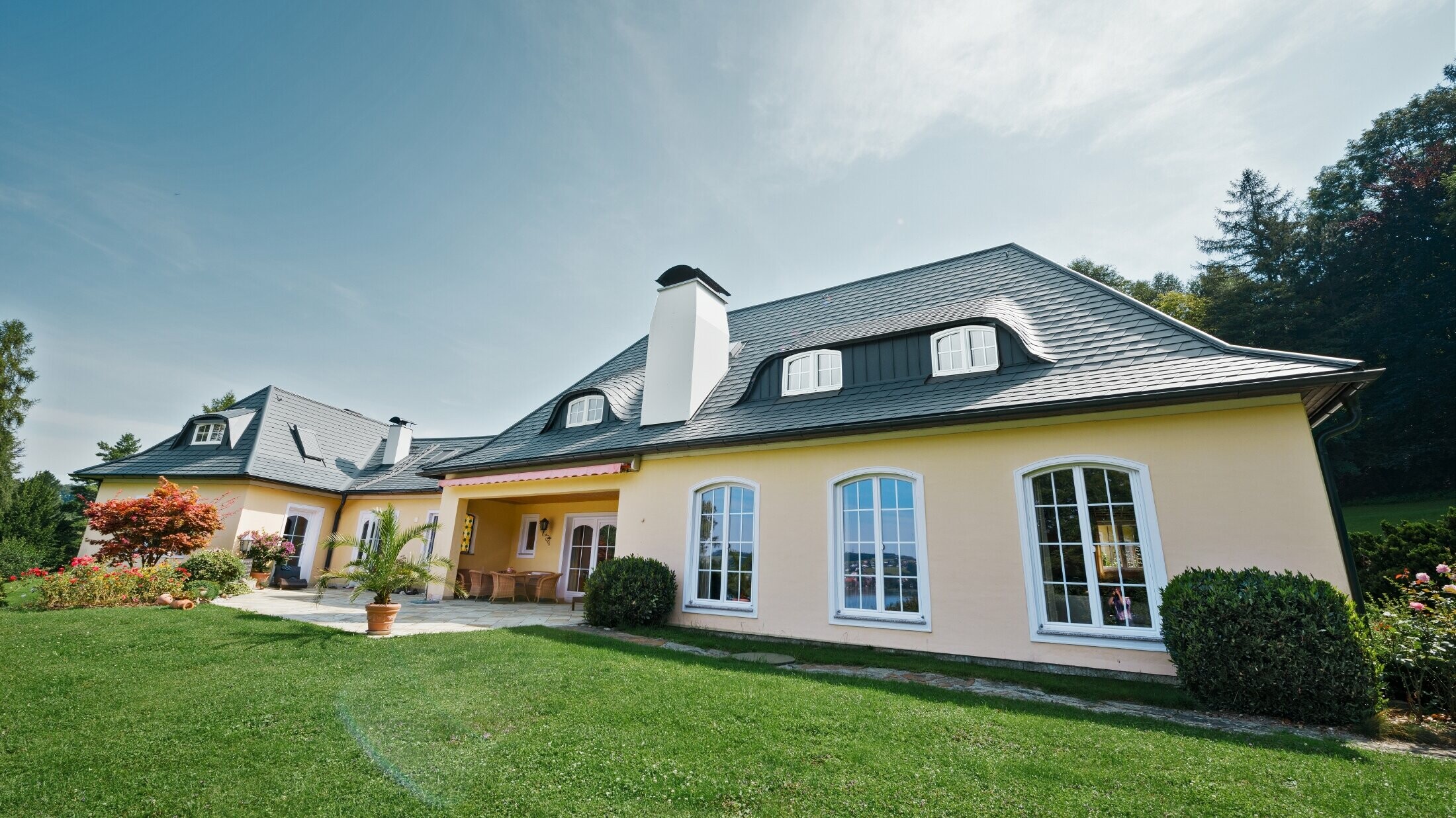 Klasický rodinný dom so zaobleným vikierom pokrytý strešným šindľom PREFA odolným voči víchrici so 40-ročnou zárukou na materiál.