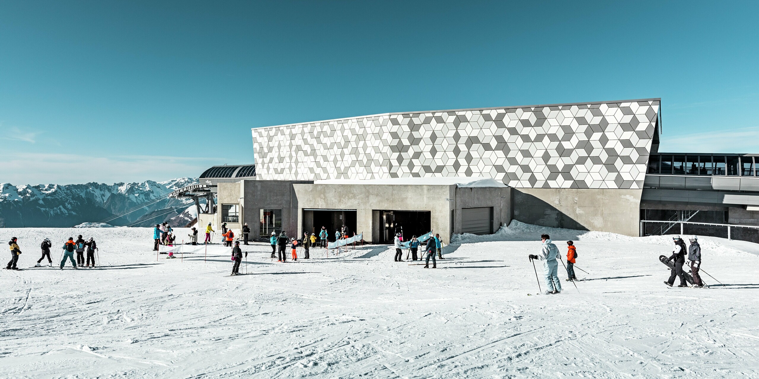 Stredná stanica lanovky 3S v Les Deux Alpes vyniká modernou fasádou. Pôsobivý plášť budovy bol navrhnutý z hliníkových kompozitných panelov PREFABOND s výrazným kosoštvorcovým vzorom. Kombinácia rôznych odtieňov bielej a sivej farby dokonale dopĺňa zasnežené okolie. Spodná časť budovy je obložená pohľadovým betónom. Robustné a poveternostným vplyvom odolné materiály nielen dobre vyzerajú, ale poskytujú aj dlhodobú ochranu pred extrémnymi poveternostnými podmienkami.