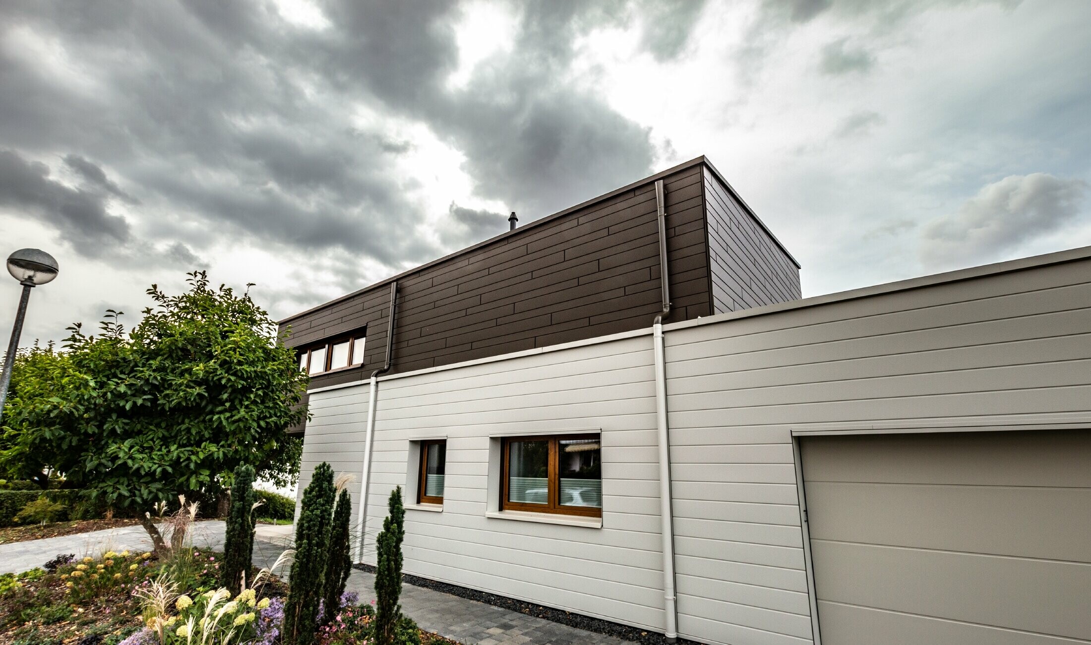 Fassadenverkleidung einer Garage mit den PREFA Sidings horizonal in Weiß, mit Speiereinmündung.