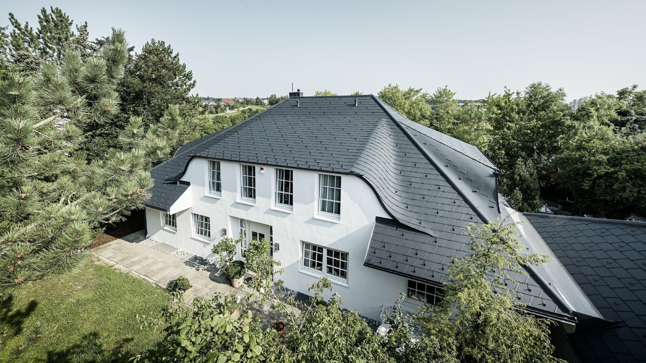 Valbová strecha so zakrivenými vikiermi, pokrytá hliníkovým strešným šindľom DS.19 vo farbe antracitová