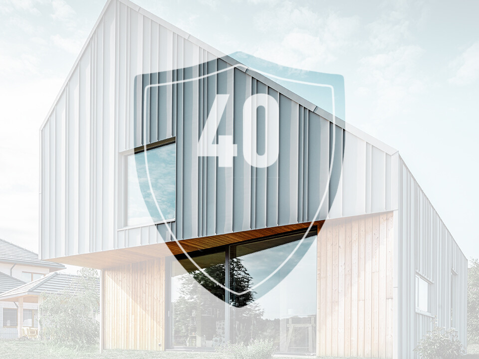 Na obrázku je pred moderným rodinným domom umiestnená tabuľa s číslom „40“, ktorá má predstavovať záruku na hliníkové výrobky PREFA.