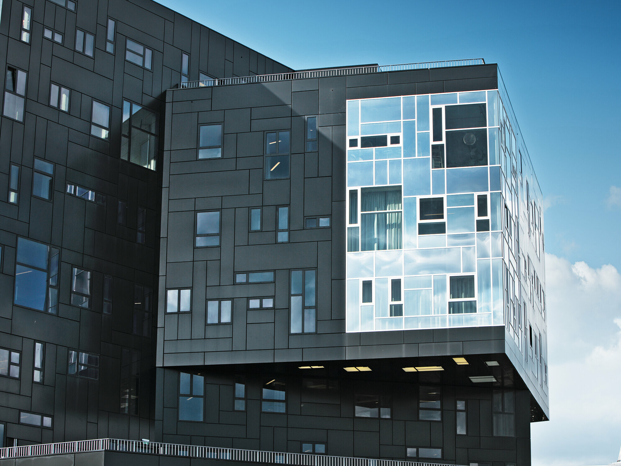 Posnetek WU Executive Academy s poudarkom na PREFA aluminijasti fasadi iz kompozitnih plošč v temno črni barvi in sijočem okenskem delu.