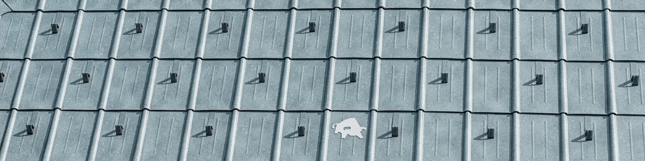 Falcovaná škridla PREFA s logom býka PREFA v kamennej šedej farbe P.10; povrch strechy s plechovou strechou PREFA