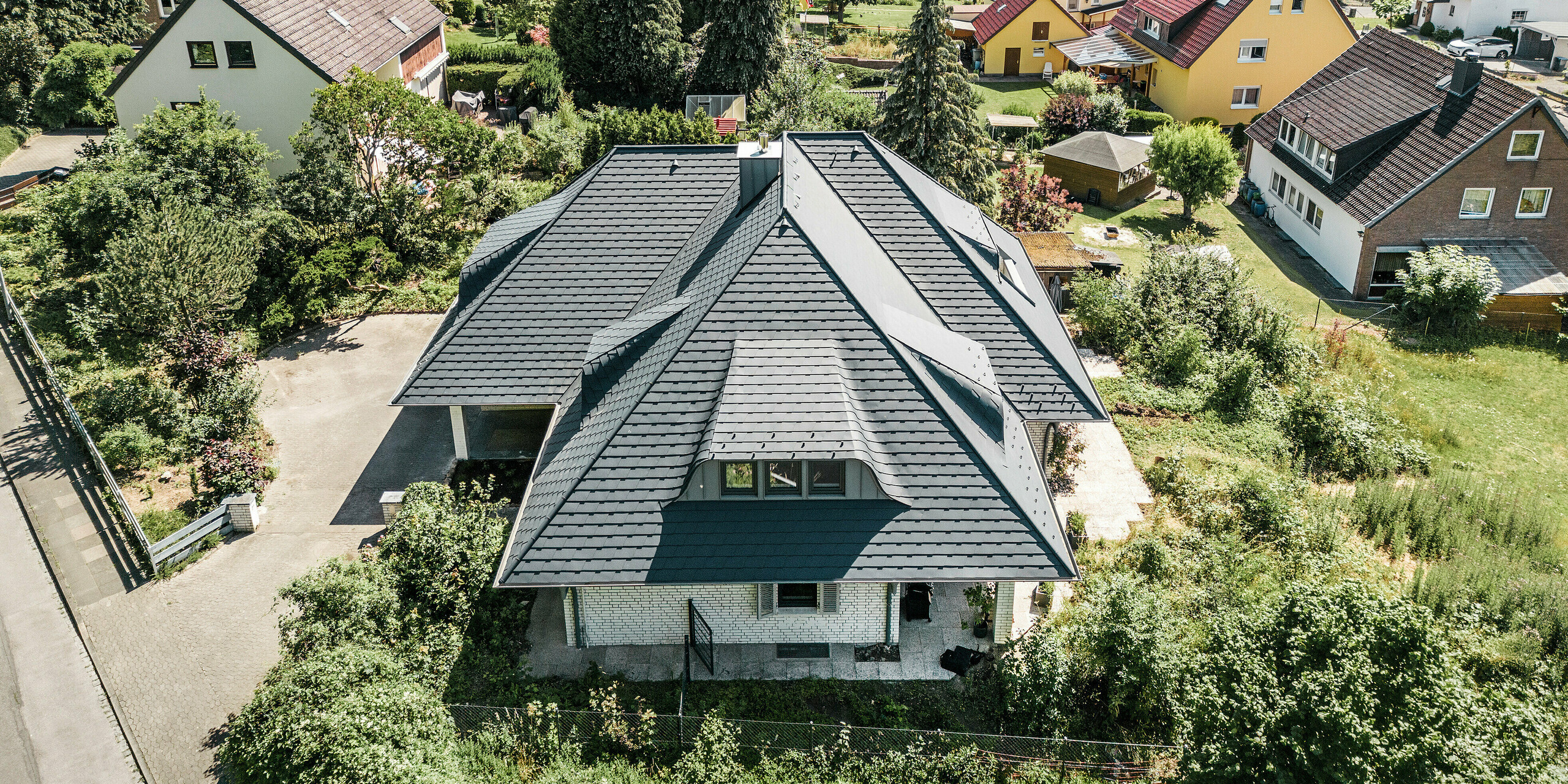 Pohľad z vtáčej perspektívy na strechu rodinného domu so strešným šindľom PREFA vo farbe P.10 antracitová