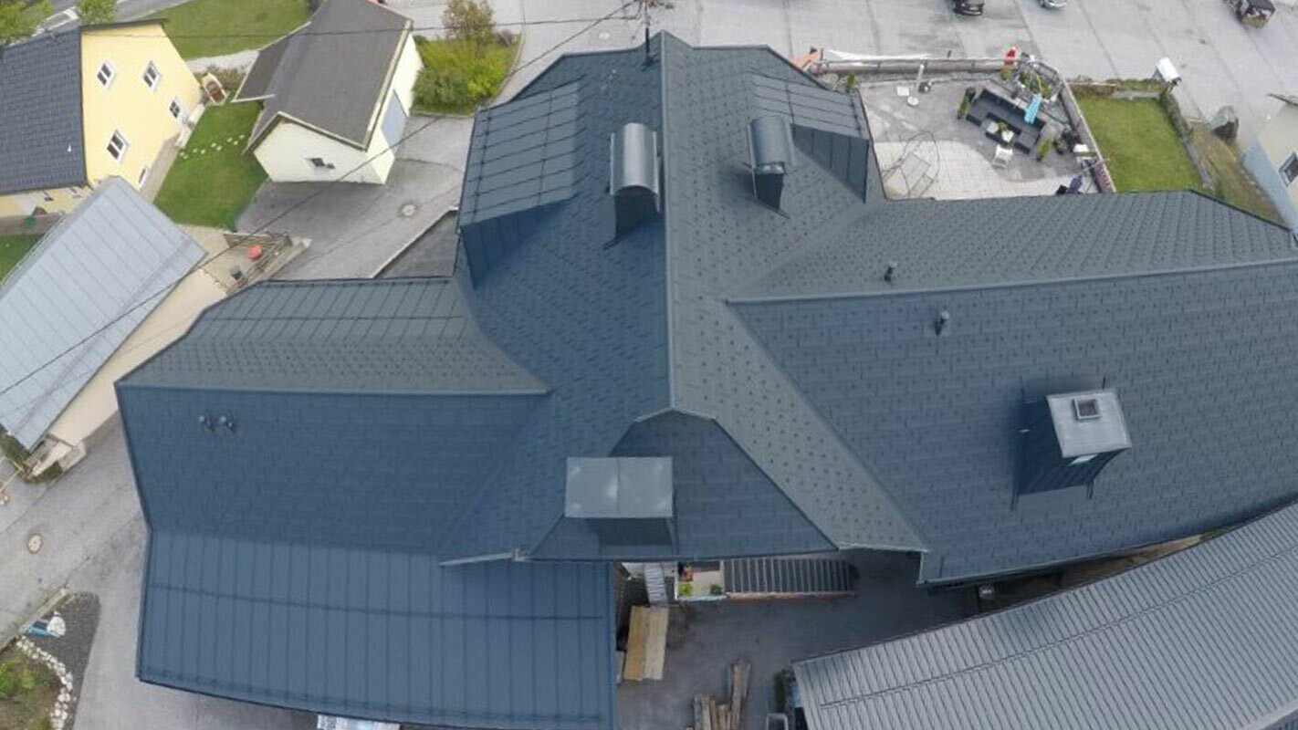 Rekonštrukcia veľkej strešnej plochy s mnohými detailami - úžľabiami, vikiermi a komínmi. Strecha je pokrytá hliníkovými PREFA strešnými panelmi R.16 antracitovej farby.