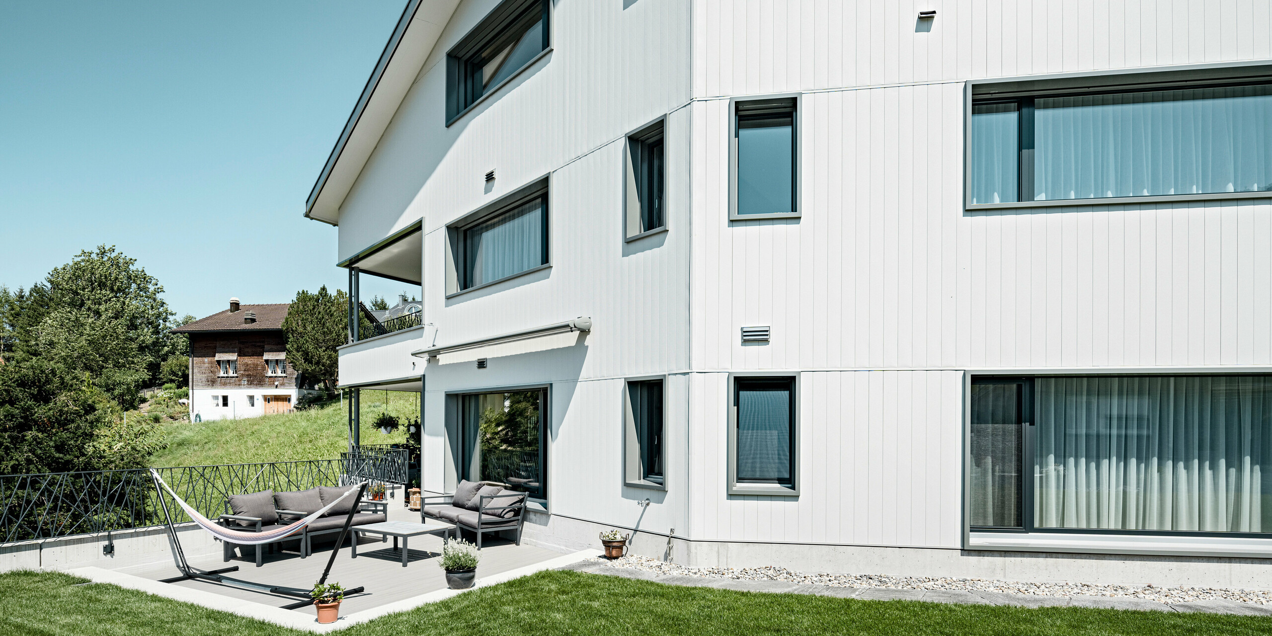 PREFA Siding vo farbe P.10 kamenná šedá a P.10 prefa biela na fasádach dvoch susedných bytových domov vo Weissbad vo Švajčiarsku.