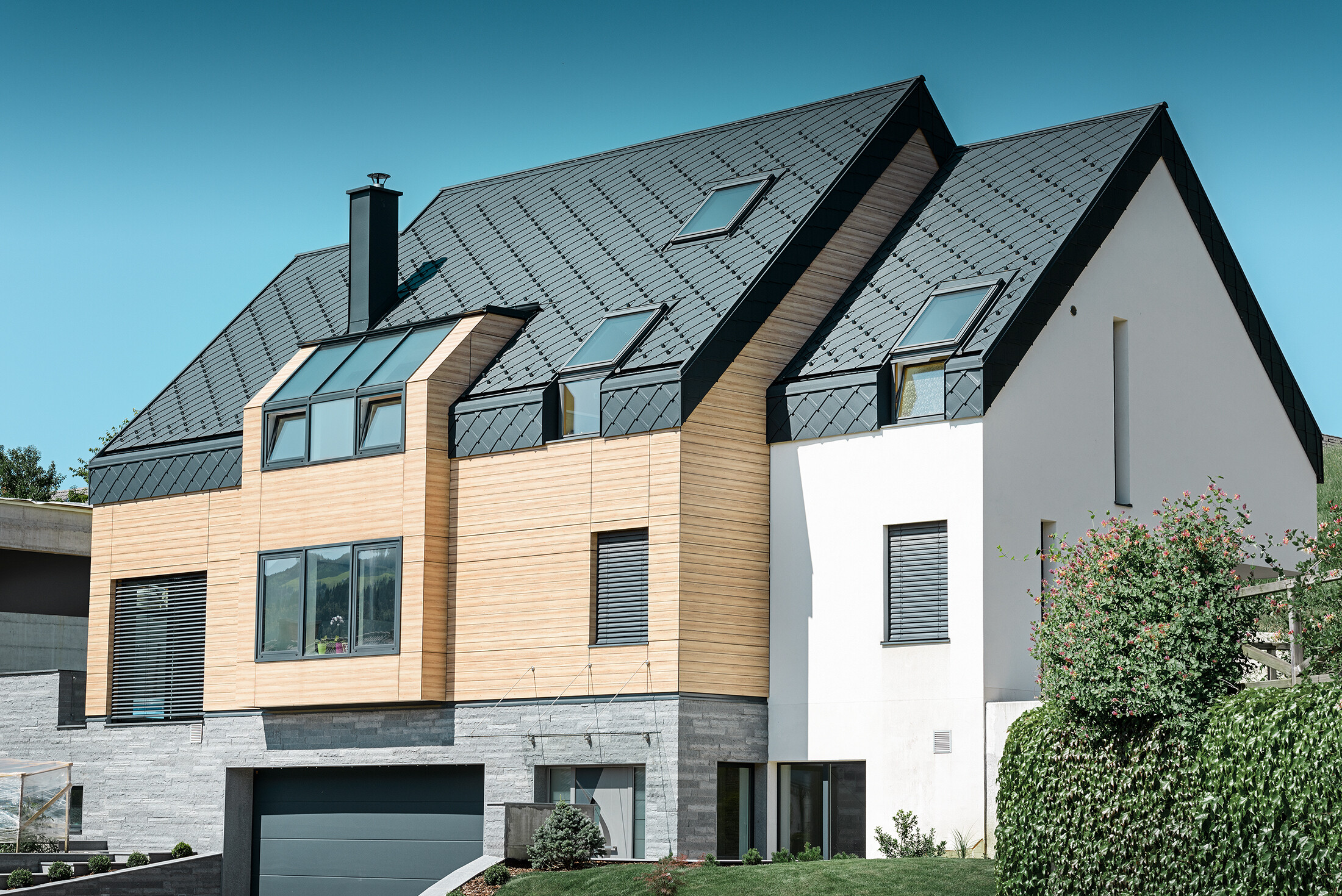 Moderná novostavba, ktorá má strešnou krytinou obloženú aj vrchnú časť fasády, ako strešná krytina bola použitá hliníková strešná šablóna v antracitovej farbe