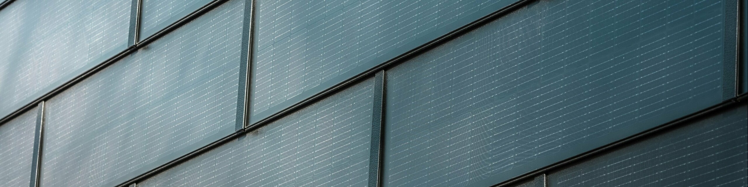 Detail fasády s integrovanými solárnymi panelmi PREFA: Fotovoltické moduly integrované do fasádneho systému vyrábajú udržateľnú elektrickú energiu a ponúkajú moderný, estetický vzhľad.