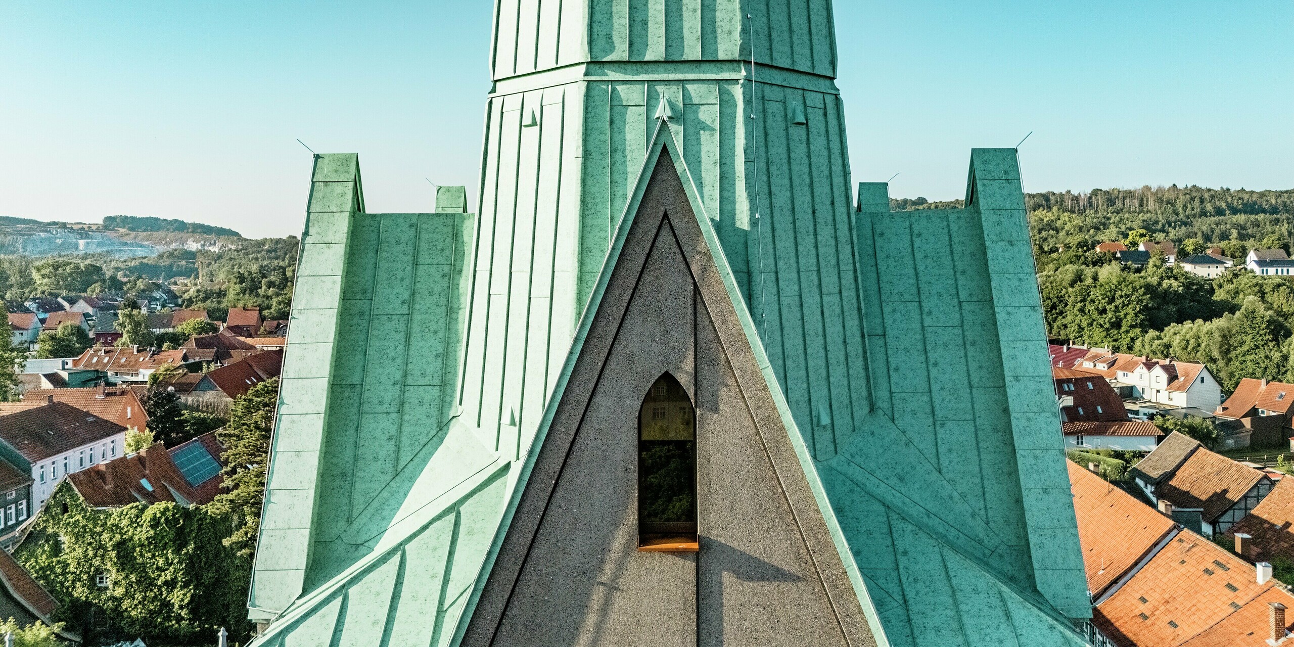 Majestätischer Blick aus nächster Nähe auf die neu errichteten Turmspitzen der Stadtkirche St. Johannis in Ellrich, eingedeckt mit PREFALZ in P.10 Patinagrün. Die markanten Stehfalze aus robustem Aluminium setzen architektonische Akzente und harmonieren perfekt mit der Umgebung. PREFALZ überzeugt durch Langlebigkeit, Wartungsfreiheit und stilvolle Ästhetik.