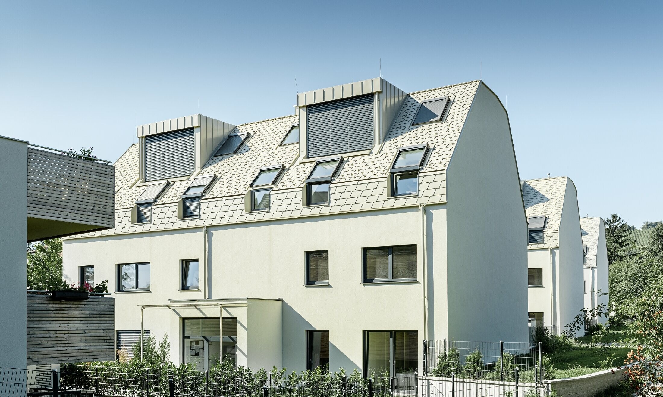 Nový bytový dom s veľkoplošnou hliníkovou strechou a mnohými strešnými oknami