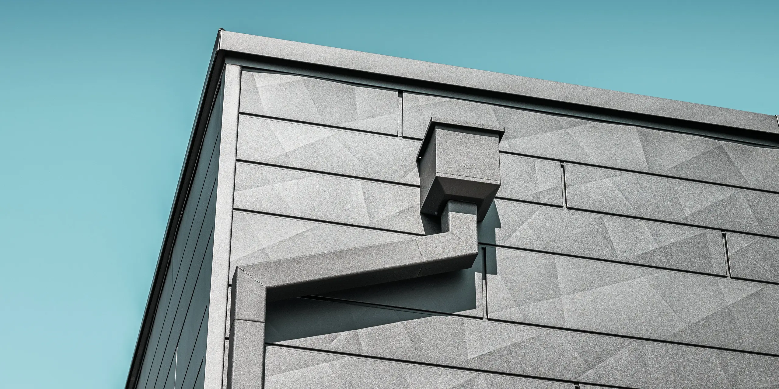  Fasádu zrekonštruovaného rodinného domu v Teuschnitzi zdobia hliníkové panely PREFA Siding.X v čiernej farbe P.10 s jedinečnou geometrickou štruktúrou. Zberný kotlík a hranatý zvod PREFA sa elegantne začleňujú do dizajnu a ponúkajú funkčné riešenie odvodnenia. Presné spracovanie a harmonické začlenenie prvkov podčiarkujú estetickú kvalitu a dlhú životnosť hliníkových produktov PREFA.