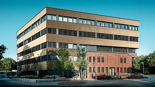 Výrazný exteriér policajnej stanice č. 43 v Hamburgu: Táto precízne členená novostavba akoby doslova vznášala nad existujúcou tehlovou budovou a zaujme hliníkovou fasádou PREFA z extrudovaných profilov „Zacke“ v elegantnom odtieni strednej bronzy. Jemne štruktúrovaný povrch vytvára v závislosti od dopadu svetla živé odlesky a dodáva budove hĺbku aj dynamiku. Ako architektonický prvok, ktorý upúta pozornosť, spája fasáda moderný dizajn s výhodami, ako je vysoká odolnosť proti korózii, dlhá životnosť a minimálne nároky na údržbu.