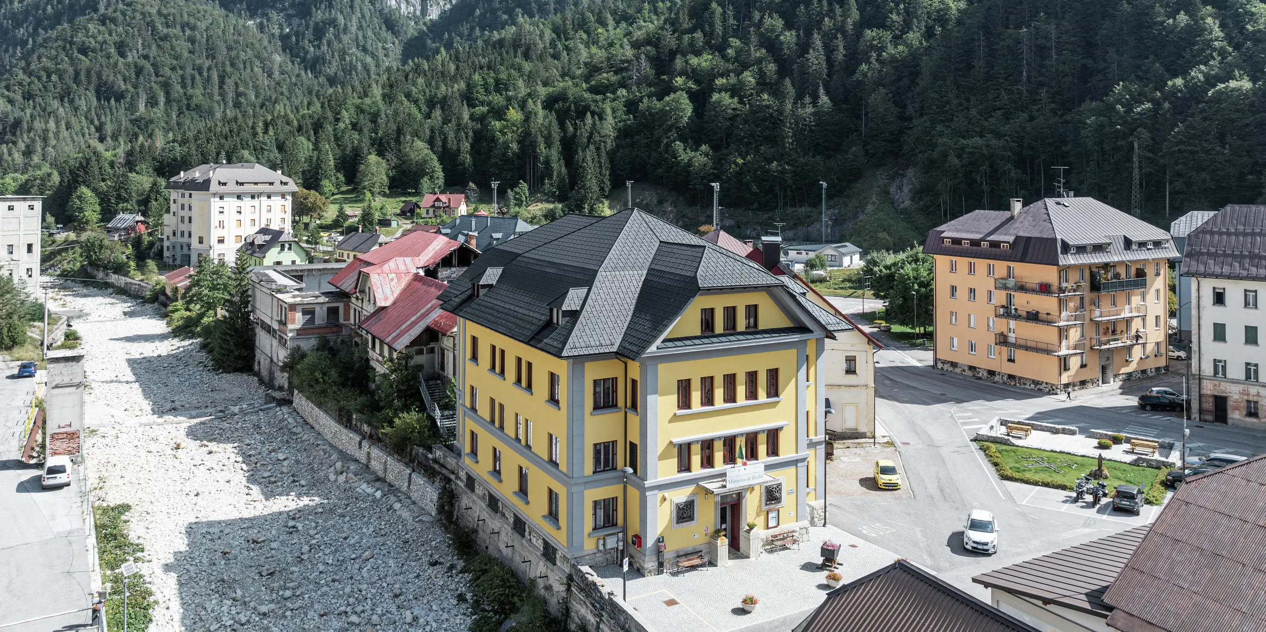 Museo Cave del Predil v Taliansku sa nachádza v pôsobivej horskej krajine. Múzeum s výraznou žltou fasádou je vybavené vysokokvalitnými falcovanými škridlami PREFA vo farbe P.10 antracit. Odolná plechová strecha zaručuje optimálnu ochranu pred alpskými poveternostnými podmienkami, ako je sneh a búrky, v spojení s estetickým dizajnom. V pozadí sa majestátne týči alpská panoráma s hustými lesmi a skalnatými vrcholmi.