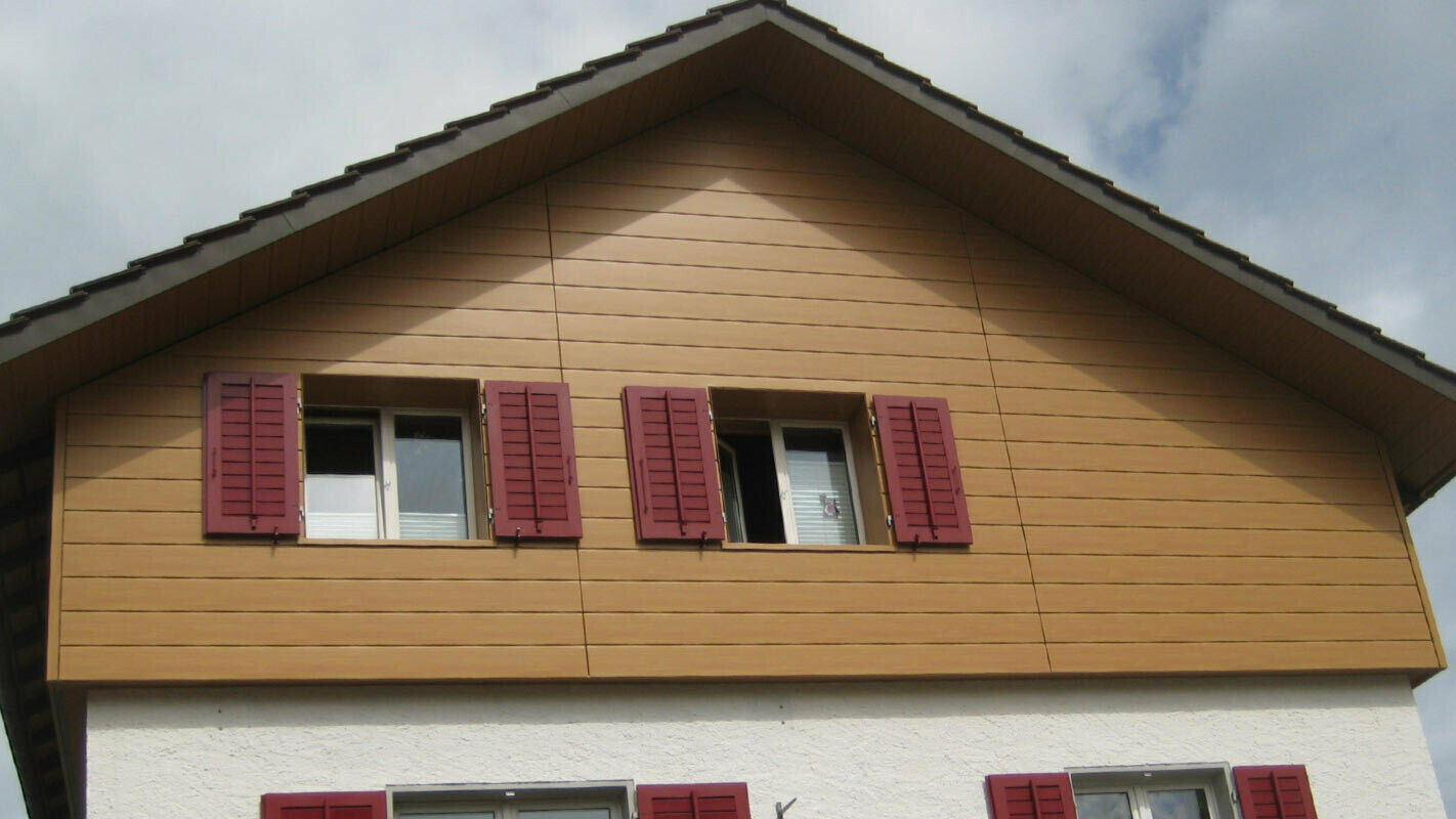 Fasáda domu s horizontálne montovanými PREFA Sidings, okna s červenými okenicami