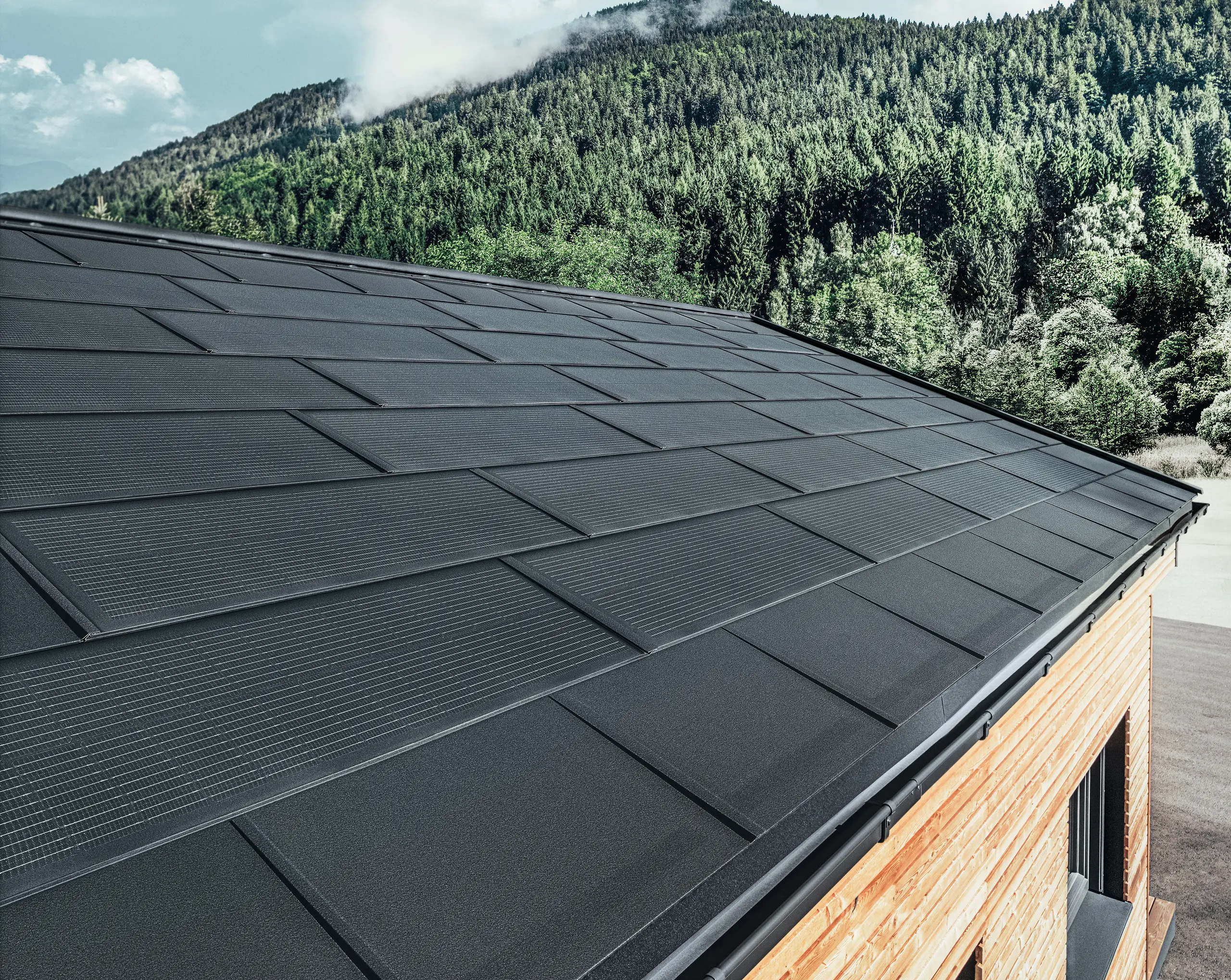 PREFA Solardachplatte in großer Ausführung kombiniert mit der Dachplatte R.16 in Schwarz, Kastenrinne und Lärchenholz-Fassade