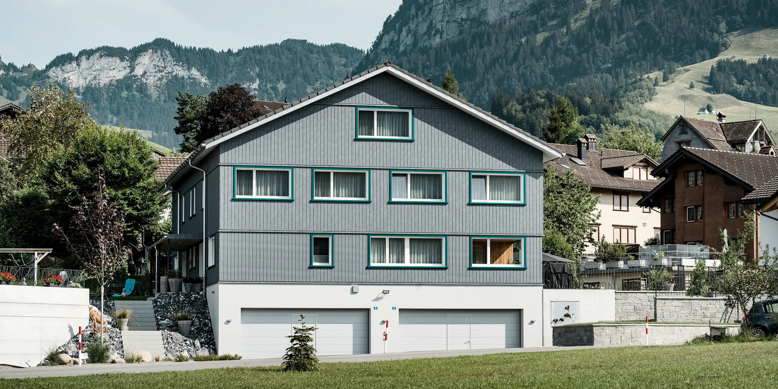 PREFA Siding vo farbe P.10 kamenná šedá a P.10 prefa biela na fasádach dvoch susedných bytových domov vo Weissbad vo Švajčiarsku.