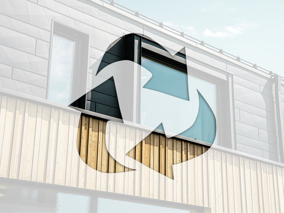 Na fotografii je symbol recyklácie pred fasádou domu s hliníkovými prvkami PREFA a drevenými panelmi.