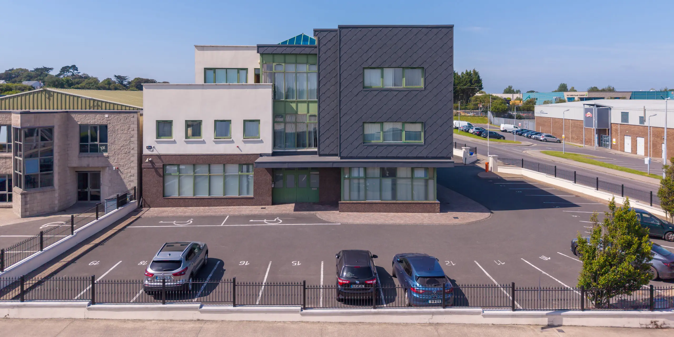 Gesamtansicht des Zentrums für psychische Gesundheit von Kindern und Jugendlichen in Wexford, Irland. Blickfang ist der markante Gebäudeteil mit PREFA Wandrauten 44 × 44 in P.10 Dunkelgrau, deren präzise Rautenstruktur der Fassade eine moderne, dynamische Optik verleiht. Die elegante Aluminiumfassade hebt sich kontrastreich von den hellen Baukörpern und großen Glasflächen ab. Das langlebige, witterungsbeständige PREFA Fassadensystem verbindet architektonische Qualität mit hoher Funktionalität und unterstreicht den zeitgemäßen Charakter des Gesundheitszentrums.