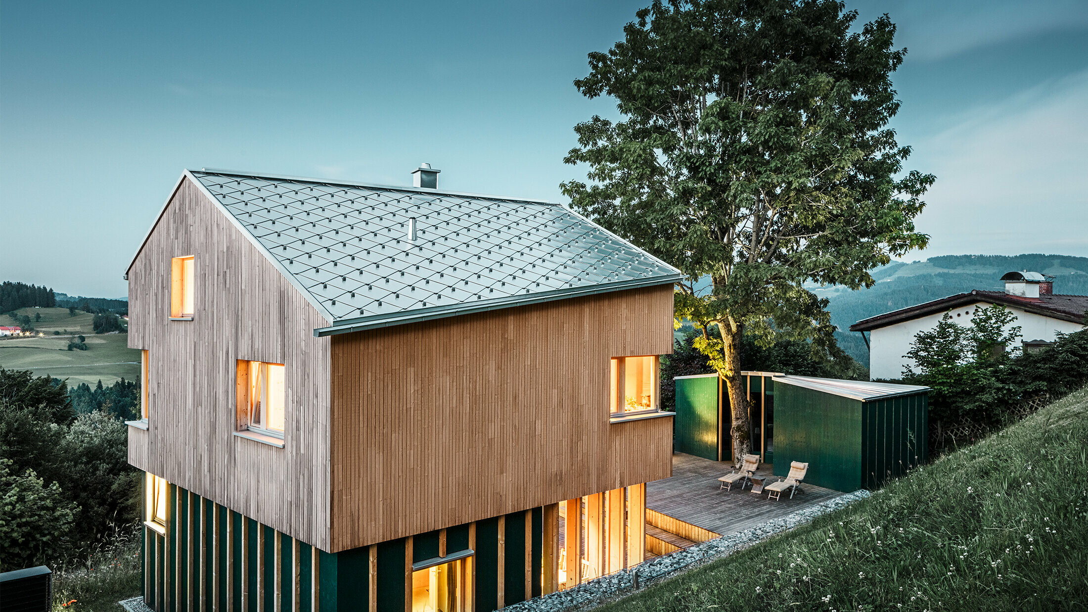 Novopostavený rodinný dom s drevenou fasádou a strechou PREFA vo forme šablóny s farbou prírodný hliník