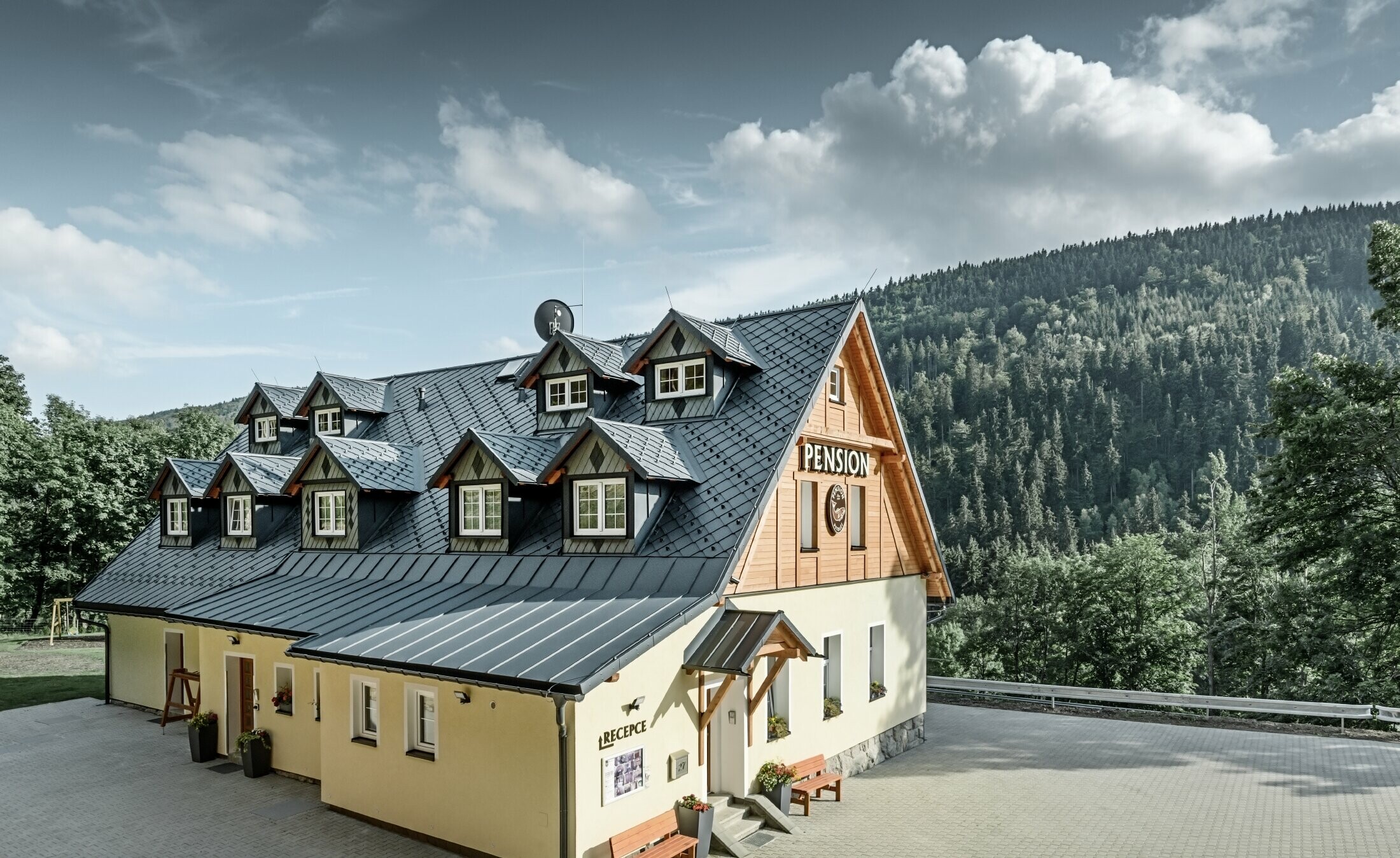 Penzión v Českej republike so šikmou strechou a množstvom vikierov, hliníková šablónová strecha PREFA so vzhľadom šupín a protisnehovou ochranou