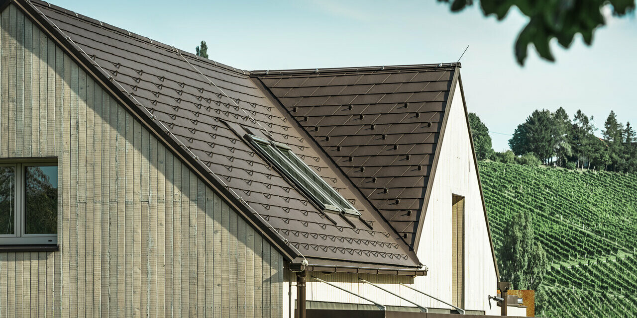 Rodinný dom s dvoma sedlovými strechami bol pokrytý s PREFA strešným šindľom vo farbe orieškovohnedá. Odvodnenie strechy je cez PREFA hranatý žľab. Fasáda je obložená so zvetraným drevom.
