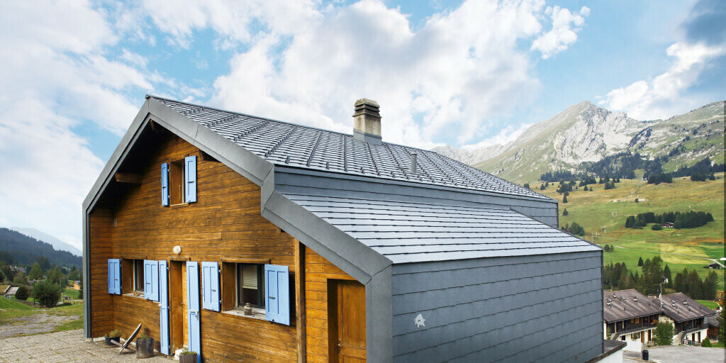 Dom v horách vo Švajčiarsku s drevenou fasádou kombinovaný s PREFA strešnou a fasádnou šablónou vo farbe kamenná šedá