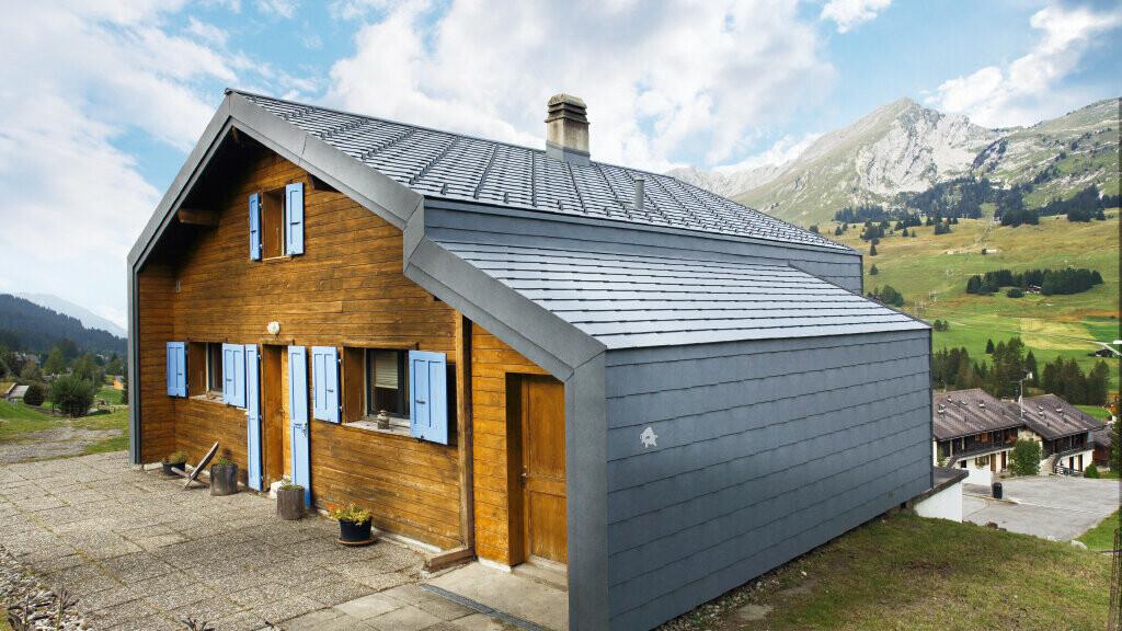 Dom v horách vo Švajčiarsku s drevenou fasádou kombinovaný s PREFA strešnou a fasádnou šablónou vo farbe kamenná šedá