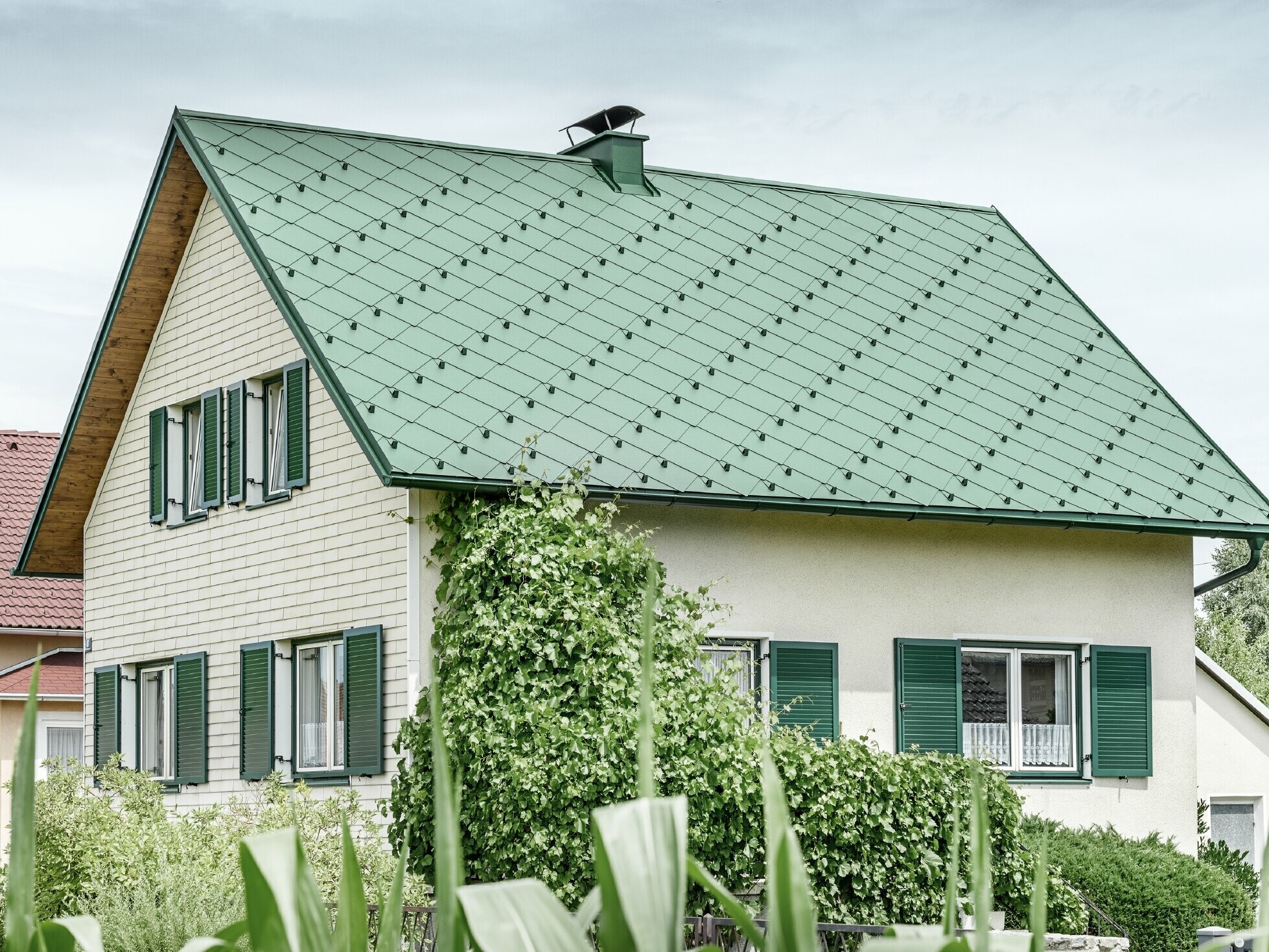 Klasický rodinný dom so sedlovou strechou so strešnou krytinou z hliníka vo farbe machovozelená so zelenými okenicami