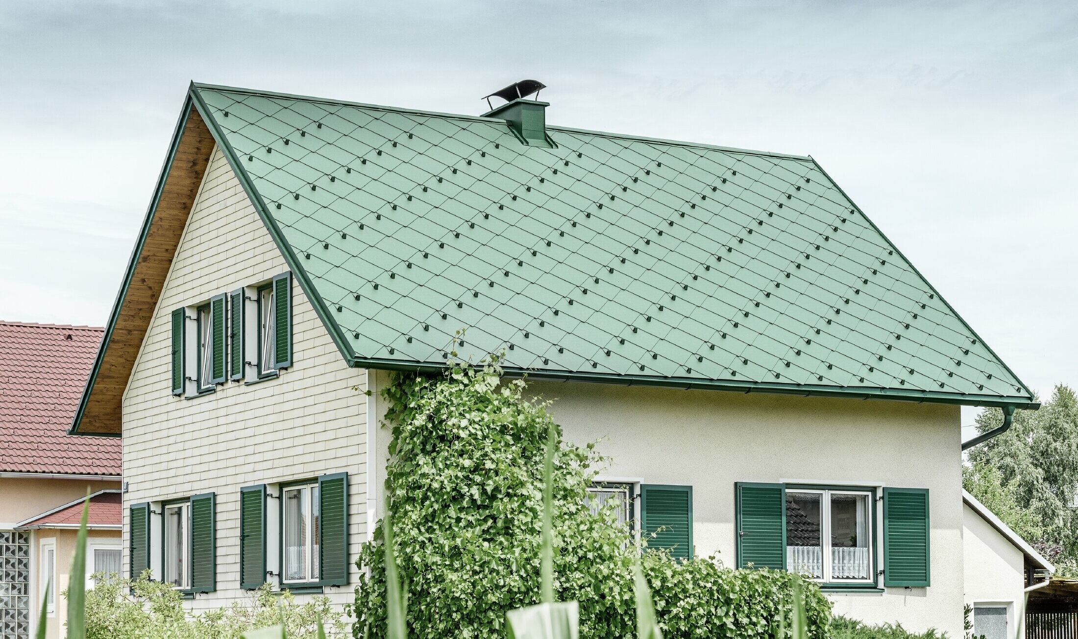 Klasický rodinný dom so sedlovou strechou so strešnou krytinou z hliníka vo farbe machovozelená so zelenými okenicami