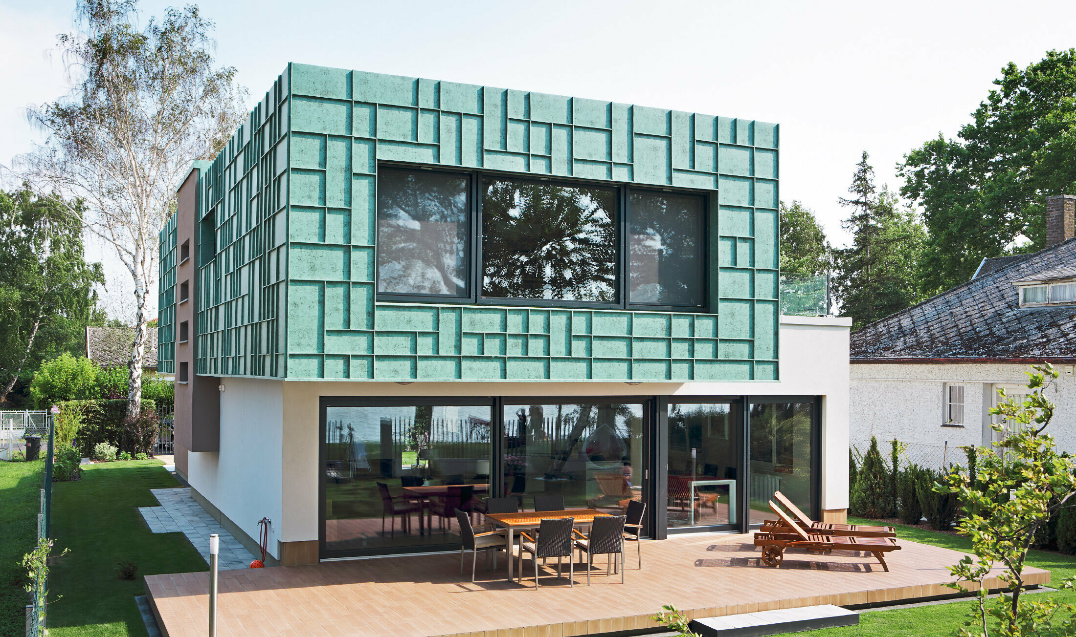 Moderný rodinný dom s fasádou odolnou voči víchrici, ktorá bola obložená systémom PREFALZ vo farebnom odtieni P.10 patina zelená.