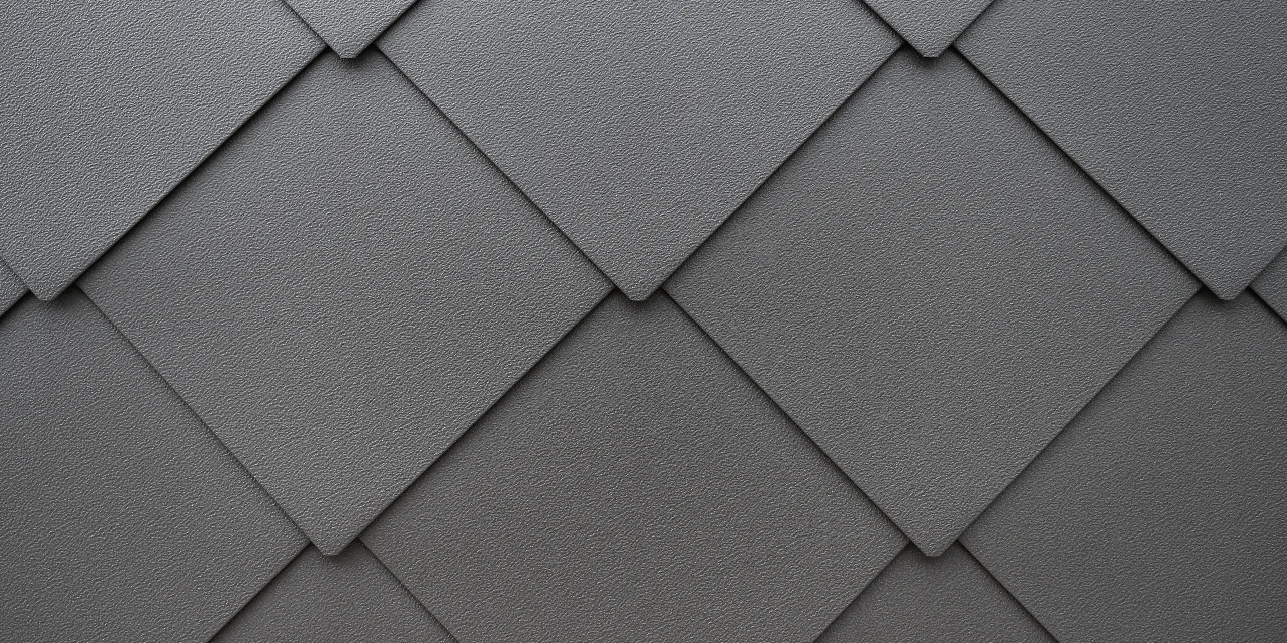 Detailný záber na štruktúrovaný povrch hliníkového fasádneho systému PREFA. Harmonické usporiadanie fasádnych šablón PREFA 44x44 vytvára jasný geometrický vzor, ktorý odráža eleganciu a modernú architektúru, zdôraznenú jemnou farebnosťou a precíznym spracovaním. Odolný plech poskytuje radovému domu v Kalterne v Južnom Tirolsku ochranu pred zimnými podmienkami.