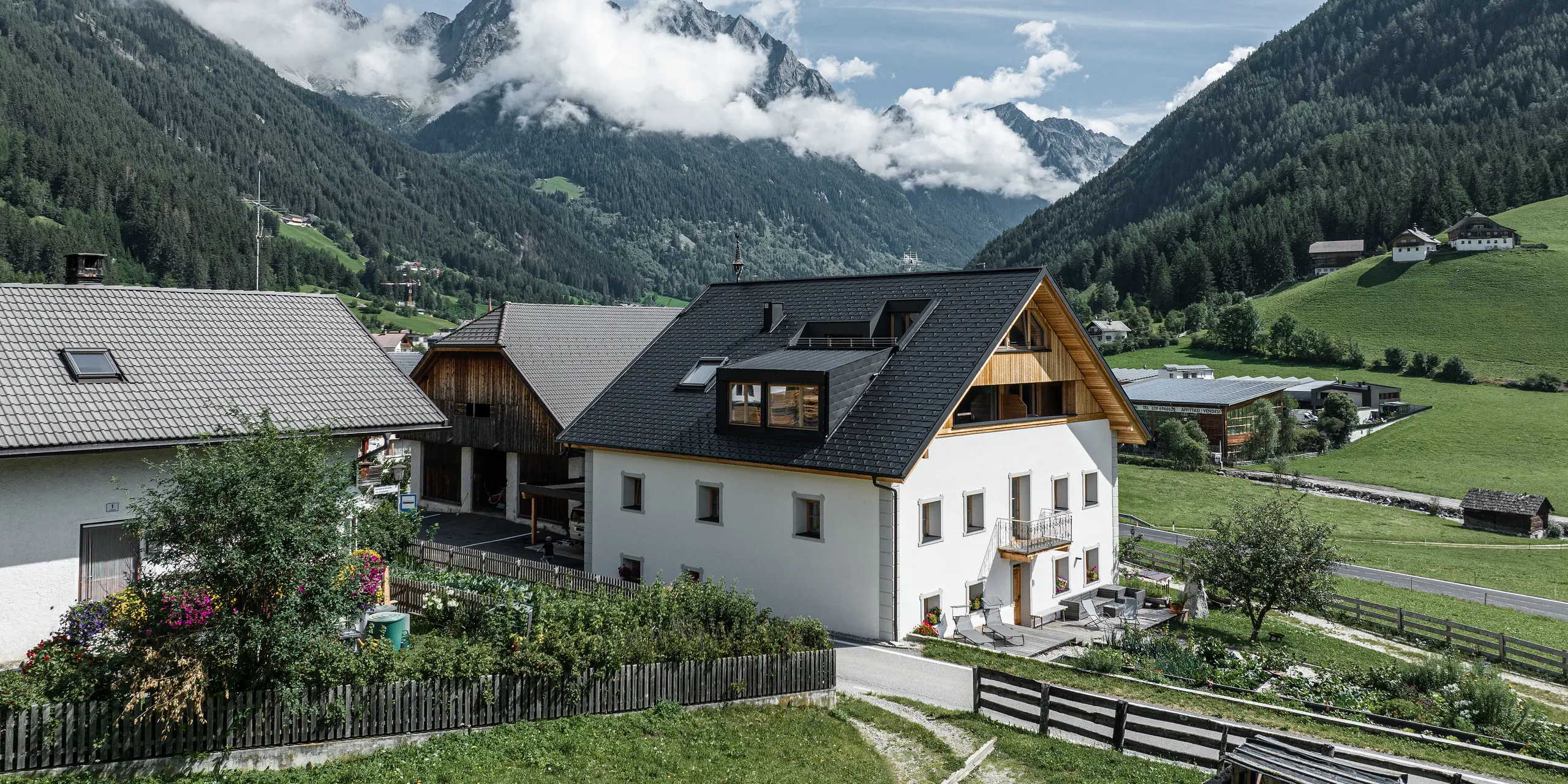 Pohľad na dovolenkové apartmány Ausserwegerhof v údolí Antholz, Južné Tirolsko, pred pôsobivou horskou kulisou. Objekt je charakterizovaný strechou PREFA so strešným šindľom DS.19 antracitovej farby. Hliníková sedlová strecha harmonicky zapadá do okolitej krajiny.
