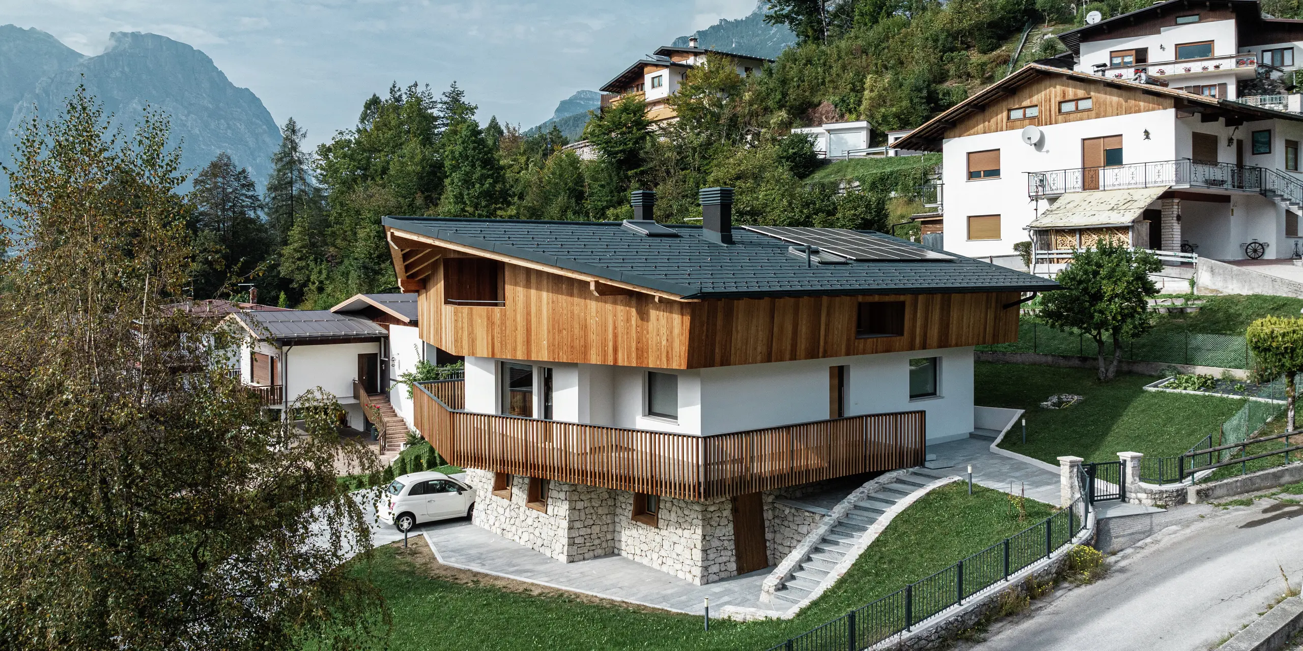 Projekt rekonštrukcie v Agorde, Taliansko: Rodinný dom bol zastrešený odolnou hliníkovou strechou PREFA vo farbe P.10 antracit. Strešný panel PREFA R.16 poskytuje spoľahlivú ochranu proti extrémnym poveternostným podmienkam a zaručuje štýlový vzhľad. Účinný odtok vody zabezpečuje aj strešný odvodňovací systém PREFA s hranatým žľabom a odvodňovacou rúrou. Kombinácia prírodnej drevenej fasády, bielej omietnutej fasády a robustnej hliníkovej strechy harmonicky zapadá do alpského prostredia.