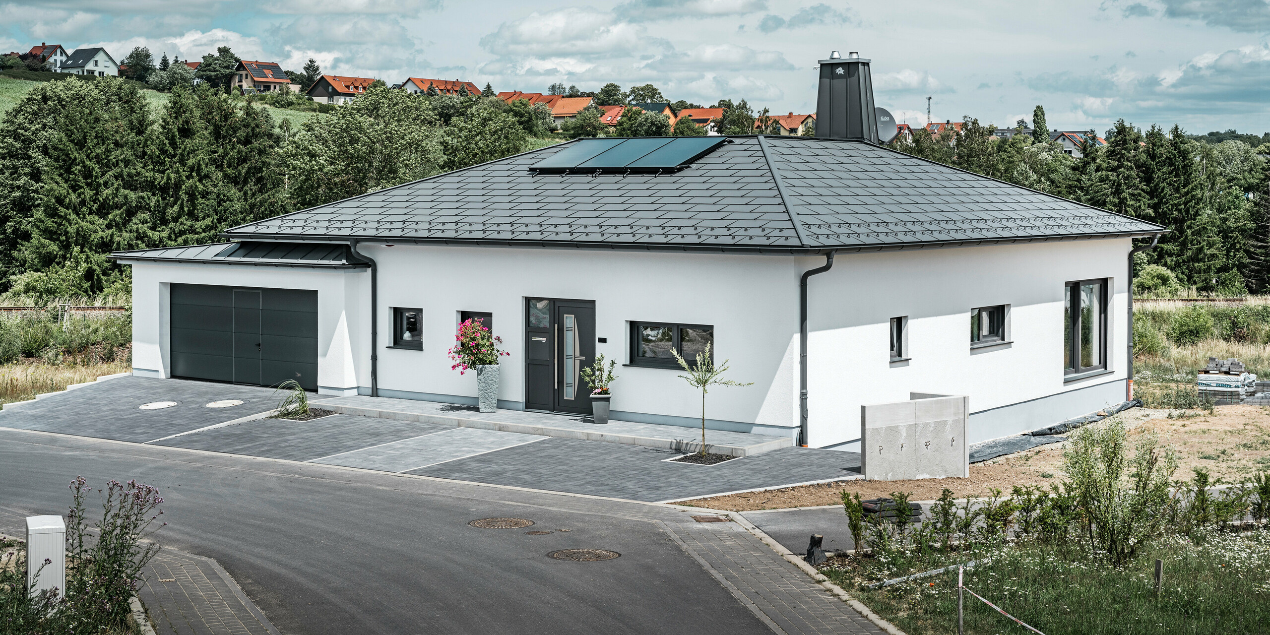 Strešný panel PREFA R.16 a PREFALZ ako aj dažďový zvod a polkruhový žľab P.10 tmavošedá na streche bungalovu