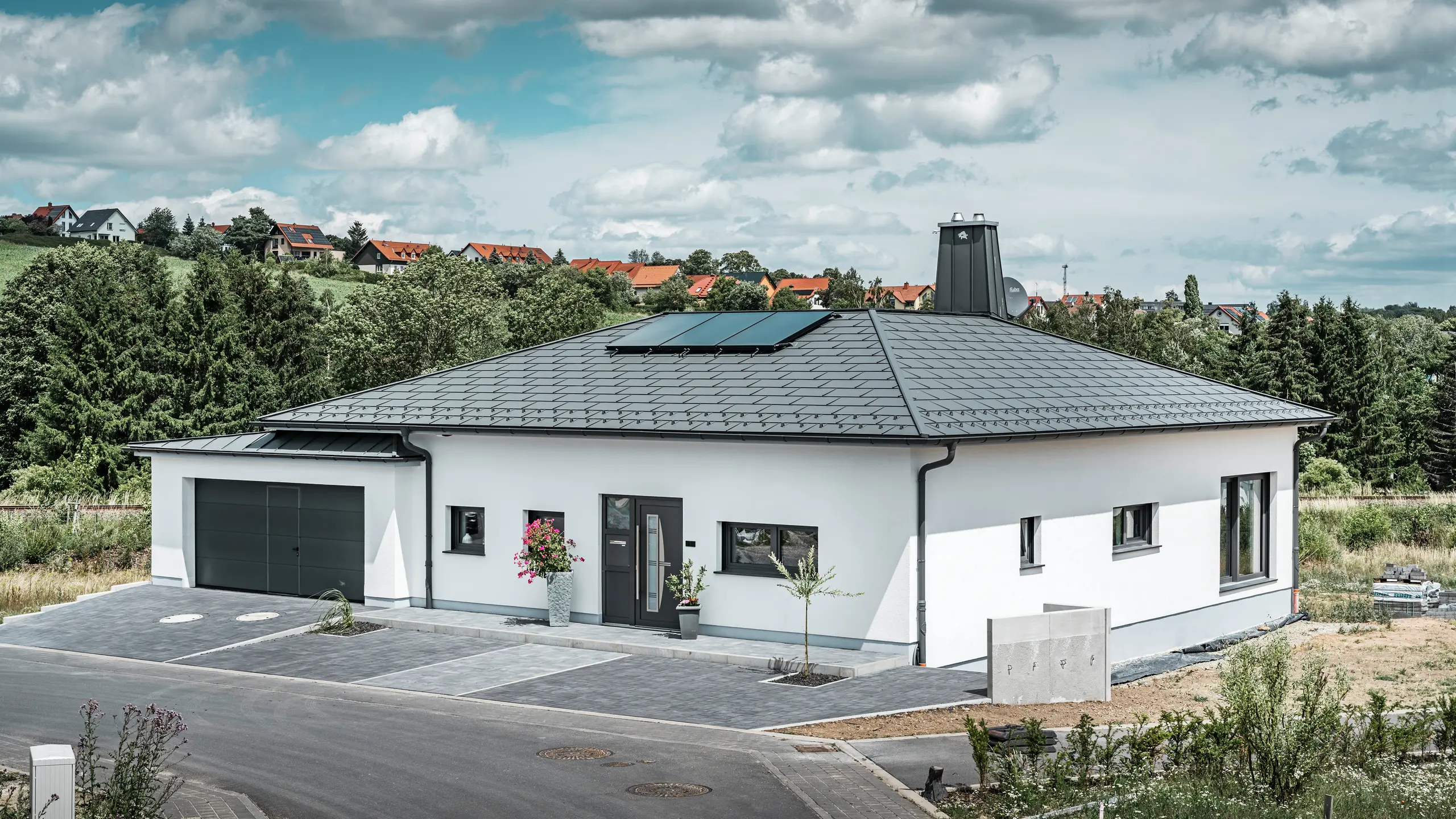 Strešný panel PREFA R.16 a PREFALZ ako aj dažďový zvod a polkruhový žľab P.10 tmavošedá na streche bungalovu