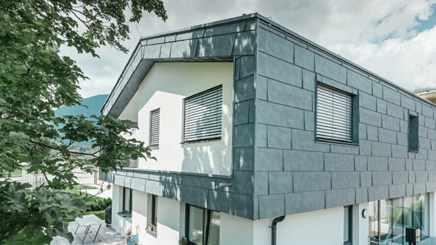 Prvé poschodie moderného obytného domu obložené hliníkovými fasádnymi panelmi PREFA FX.12 vo farbe kamenná šedá.