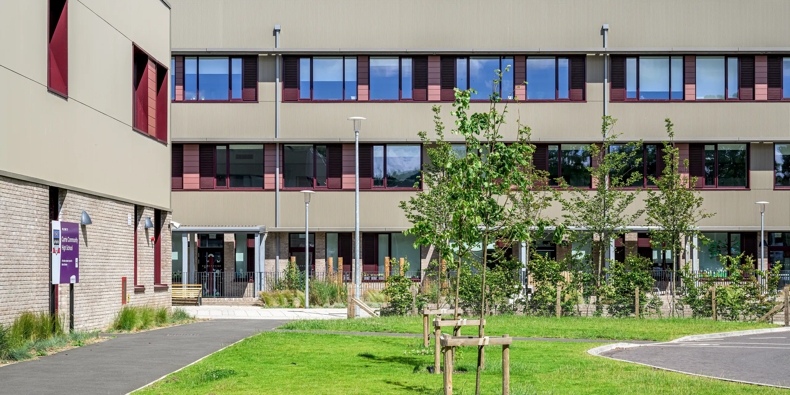 Die Fassadenansicht der Currie Community High School in Edinburgh zeigt die großflächige PREFA Aluminiumfassade mit Strangpressprofil Zacke in P.10 Prefabronze. Die fein strukturierte, vertikale Profilierung verleiht dem Schulgebäude eine lebendige Optik und setzt elegante Kontraste zu den dunklen Fensterrahmen. Das langlebige, korrosionsbeständige und wartungsarme PREFA Aluminiumsystem verbindet moderne Architektur mit nachhaltiger Funktionalität und hoher Gestaltungsqualität.