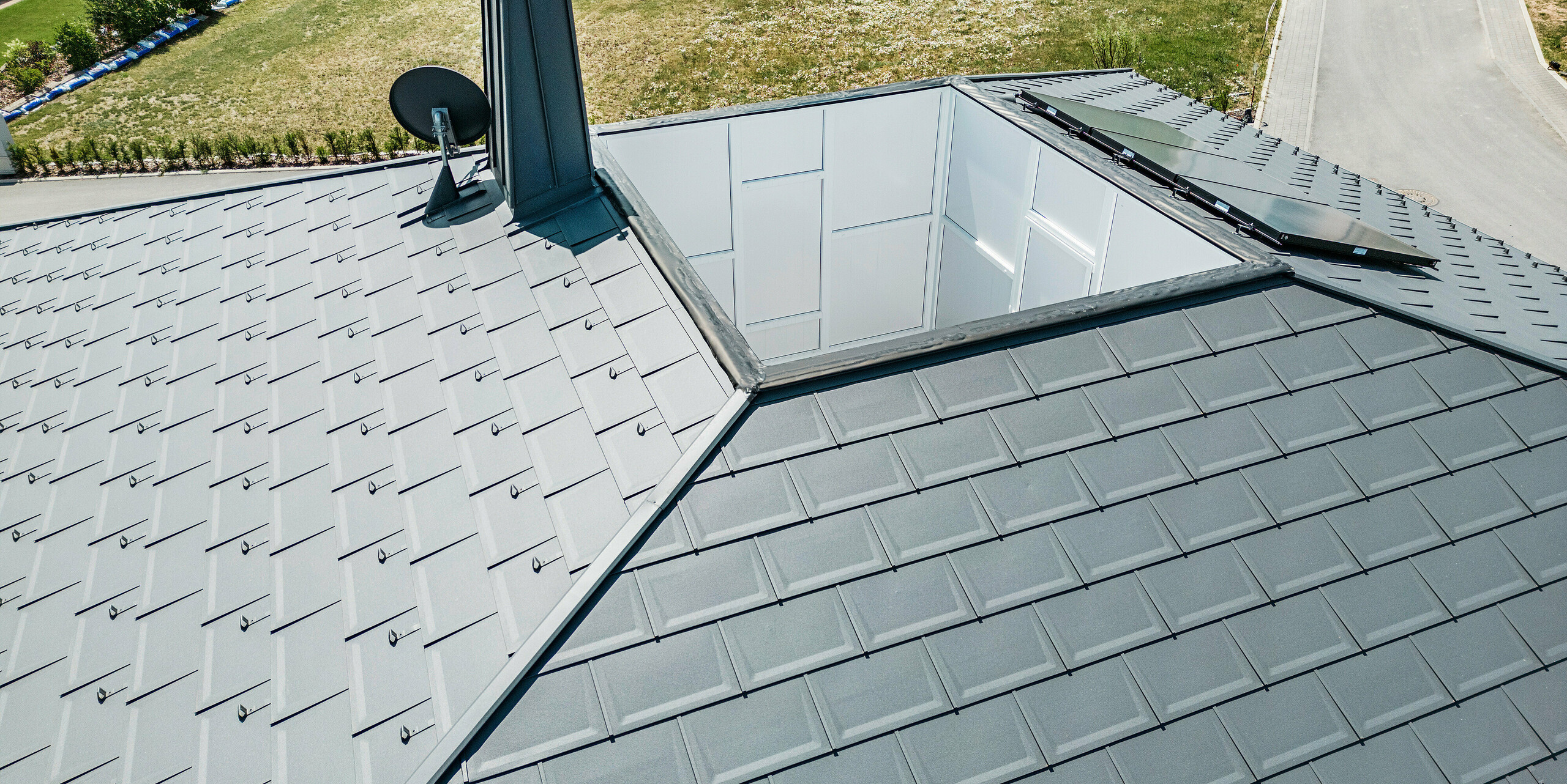 Strešný panel PREFA R.16 a PREFALZ ako aj dažďový zvod a polkruhový žľab P.10 tmavošedá na streche bungalovu