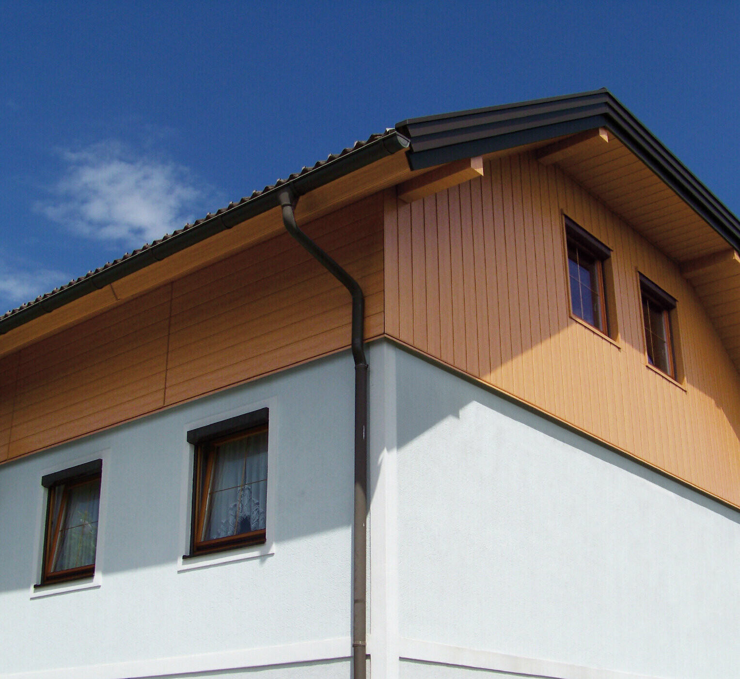 Veľký rodinný dom s polvalbovou strechou s obkladom štítu s fasádnymi panelmi PREFA Siding vo vzhľade dreva (farba prírodný dub)