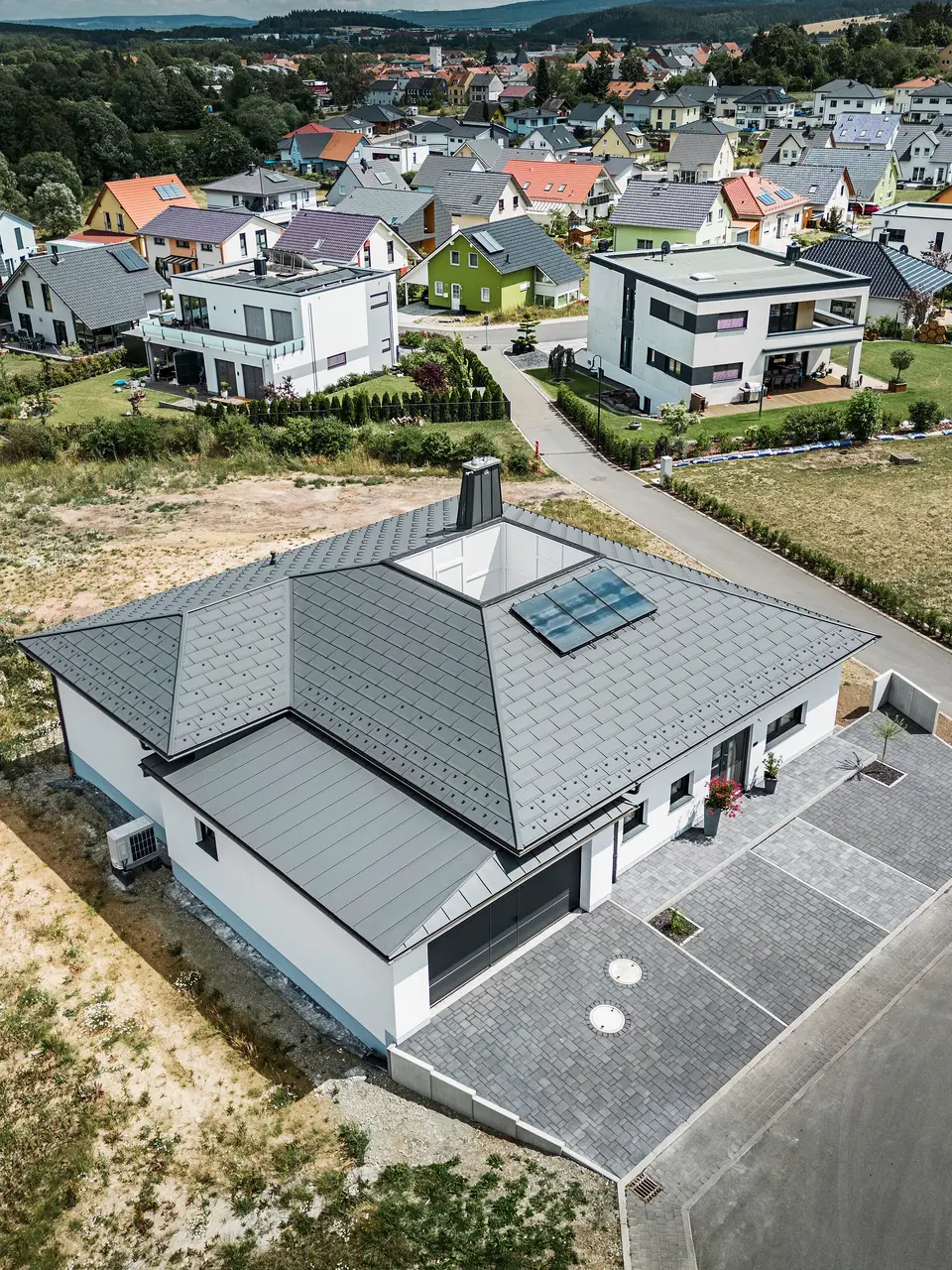 Strešný panel PREFA R.16 a PREFALZ ako aj dažďový zvod a polkruhový žľab P.10 tmavošedá na streche bungalovu