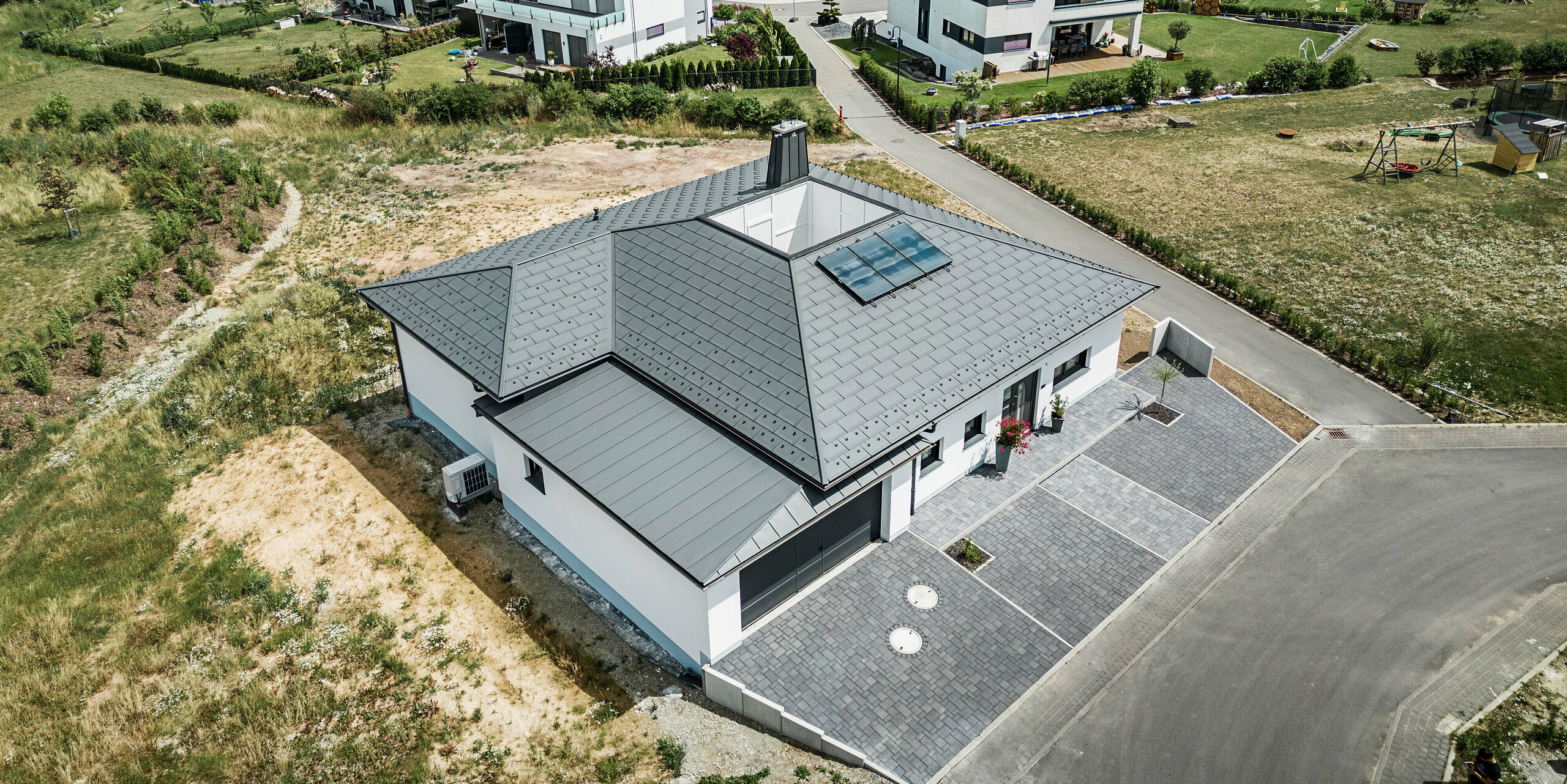 Strešný panel PREFA R.16 a PREFALZ ako aj dažďový zvod a polkruhový žľab P.10 tmavošedá na streche bungalovu