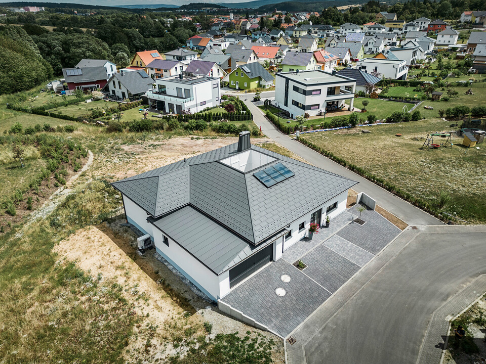 Strešný panel PREFA R.16 a PREFALZ ako aj dažďový zvod a polkruhový žľab P.10 tmavošedá na streche bungalovu